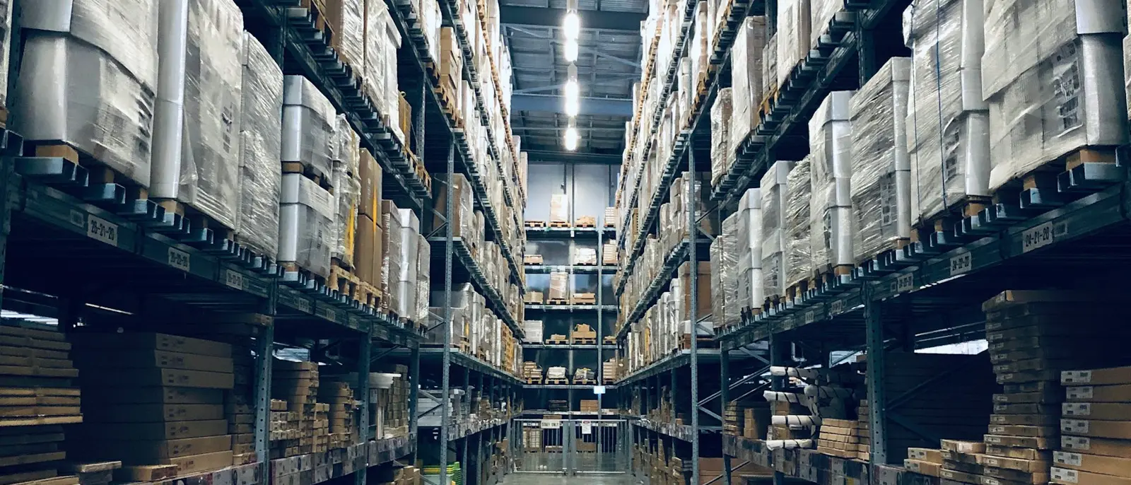 A warehouse aisle with goods stacked on high shelves